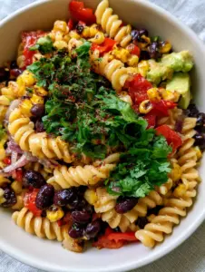 Top-down angled close-up of fusilli pasta mixed with fire-roasted corn and glossy black beans. (black bean and corn pasta salad)