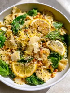 Top-down macro shot of Lemon Basil pasta Salad showing translucent vinaigrette highlights on farfalle ribbons. (Lemon Basil pasta Salad)