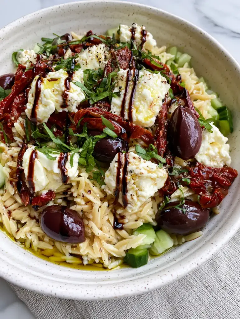 Balsamic Orzo Salad with Creamy Feta and Sun-Dried Tomatoes 1 Close up of oil-packed sun-dried tomatoes and whole kalamata olives in a balsamic orzo salad.