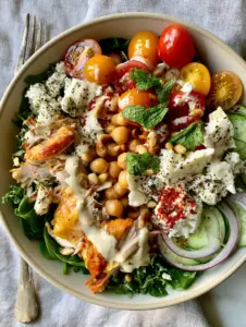 Overhead view of a vibrant Mediterranean power bowl with shredded kale, chicken, and lemon-tahini dressing for summer dinner recipes.